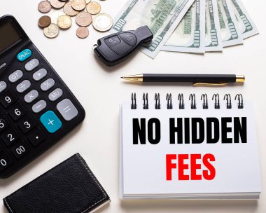 Beyaz bir masada hesap makinesi, araba anahtarı, nakit para, bir kalem ve üzerinde No GIDDEN FEES yazan bir defter var.