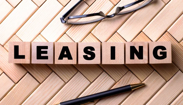 Kalem ve gözlüklerin yanındaki tahta bir arka planda, ahşap küplere yazılır..