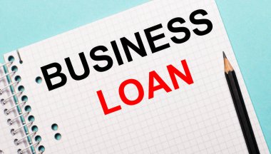 Açık mavi bir arkaplanda, üzerinde BUSINESS kredisi ve siyah kalem yazan kareli bir defter..