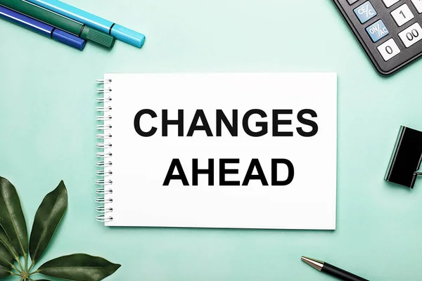 CHANGES AHEAD is written on a white sheet on a blue background near the stationery and the Scheffler sheet. Call to action. Motivational concept