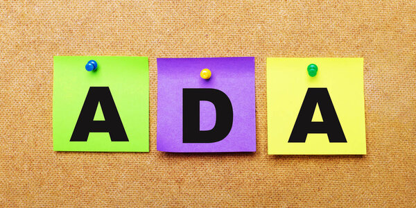На бежевом фоне разноцветные наклейки для заметок со словом ADA Americans with Disabilities Act
