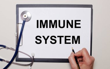 Hafif bir arka plan, bir steteskop ve üzerine IMMUNE SİSTEM yazan bir kağıt. Tıbbi konsept