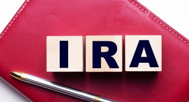 IRA Bireysel Emeklilik Hesabı ağılın yanındaki bordo bir defterin üzerinde duran tahta küplerden oluşuyor. İş konsepti