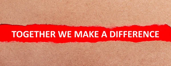 A strip of red paper under the torn brown paper. White lettering on red paper TOGETHER WE MAKE A DIFFERENCE. View from above