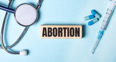 Mavi arka planda bir steteskop, bir şırınga ve haplar ve üzerinde 