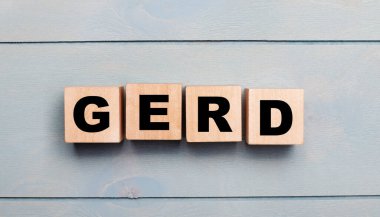 Açık mavi ahşap zemin üzerinde GERD yazılı tahta küpleri.