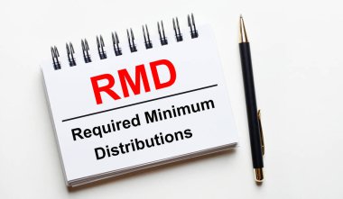 Hafif bir arkaplanda, RMD içeren beyaz bir defter Minimum Dağıtım ve bir kalem gerektiriyor.