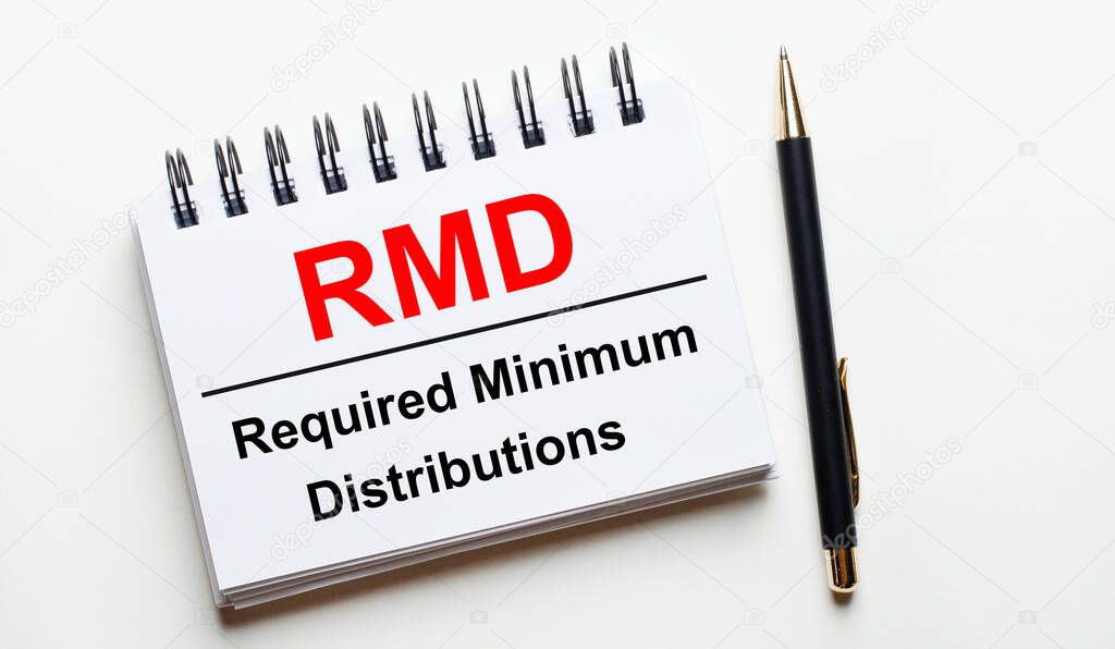 On a light background, a white notebook with are words RMD Required Minimum Distributions and a pen.