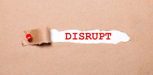 Kırmızı düğmeyle tutturulmuş kraft kağıdının altında DISRUPT etiketli beyaz bir kağıt var.