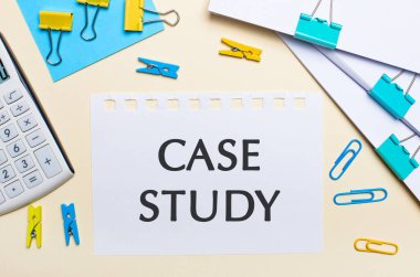 Hafif bir arka planda, bir yığın belge, bir beyaz hesap makinesi, sarı ve mavi ataçlar ve mandallar ve CASE STUDY yazılı bir defter var.