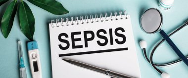Mavi arka planda beyaz bir defterde, bir katman kılıf, bir stetoskop, bir şırınga ve bir elektronik termometre yanında SEPSIS kelimesi yazılır. Tıbbi konsept