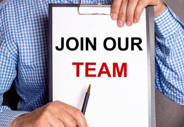 The man points with a pen to the text JOIN OUR TEAM on a white sheet.
