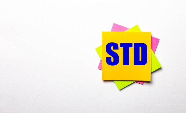 On a light background - bright multicolored stickers with the text STD. Copy space