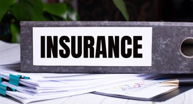 INSURANCE kelimesi belgelerin yanındaki gri bir dosya klasörüne yazılmıştır. İş konsepti