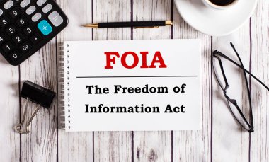 FOIA Bilgi Özgürlüğü Yasası bir hesap makinesinin, kahvenin, bardakların ve kalemin yanında beyaz bir not defterine yazılır. İş konsepti