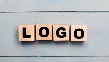 Açık mavi ahşap zemin üzerinde LOGO yazılı tahta küpler..