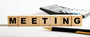 Hafif bir arka planda, bir kalem, hesap makinesi ve yazılı olan ahşap küpler. Odaklanmayın