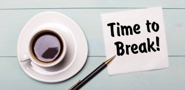 Açık mavi bir ahşap tepside beyaz bir fincan kahve, bir kulp ve kırılma zamanı yazan bir peçete var.