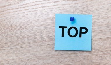 Açık ahşap bir arkaplanda - açık mavi bir kare etiketi üzerinde TOP yazılı