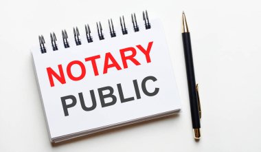 Hafif bir arkaplanda, beyaz bir defter, içinde kelimeler olan NOTARY PUBLIC ve bir kalem.