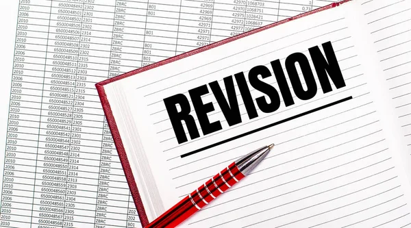 Raporların yanındaki masada REVISION yazılı bir günlük var. Yakınlarda kırmızı bir kol var..