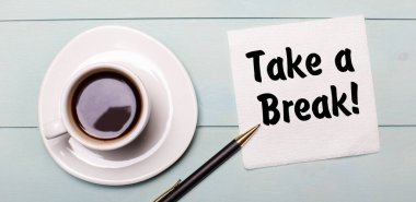 Açık mavi bir ahşap tepside beyaz bir fincan kahve, bir kulp ve bir peçete var.