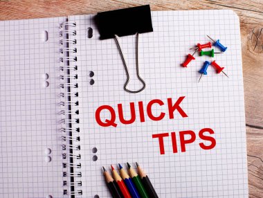 QUICK TIPS kelimeleri çok renkli kalemler ve ahşap bir arka planda düğmeler yakınında bir deftere yazılmıştır..