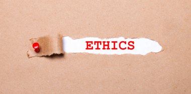 Beneath the torn strip of kraft paper attached with a red button is a white paper labeled ETHICS