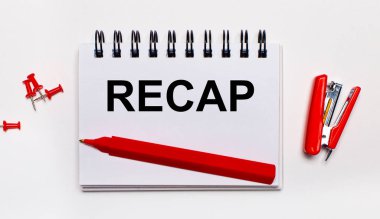 On a light background, a red pen, a red stapler, red paper clips and a notebook with the inscription RECAP