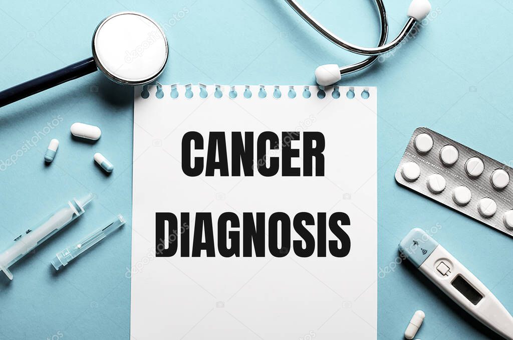 The words CANCER DIAGNOSIS written on a white notepad on a blue background near a stethoscope, syringe, electronic thermometer and pills. Medical concept