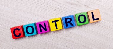 On a light wooden background on multi-colored bright wooden cubes the word CONTROL