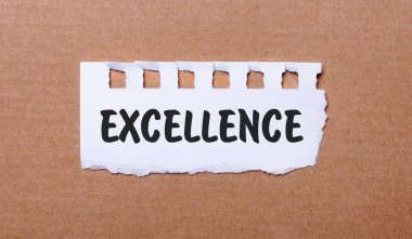 On a brown background, white paper with the inscription EXCELLENCE