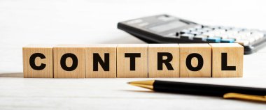 Hafif bir arka planda, bir kalem, hesap makinesi ve üzerinde kontrol yazıları olan tahta küpler. Odaklanmayın