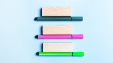 Açık mavi arka planda üç renkli keçeli kalem ve tahta bloklar bulunur. Şablon. Boşluğu kopyala