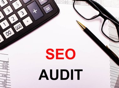 Raporlarda bir hesap makinesi, gözlük, kalem ve SEO AUDIT yazılı bir defter var.