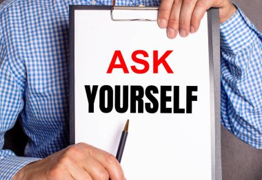 Adam beyaz bir sayfa üzerinde kendine soru soran bir kalemle işaret eder..