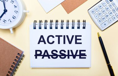 Hafif bir arkaplanda, beyaz bir çalar saat, bir hesap makinesi, bir kalem ve üzerinde Aktif metin olan bir defter. Düz yatıyordu