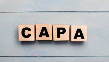 Açık mavi ahşap zemin üzerinde CAPA yazılı tahta küpler..