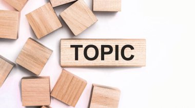 Hafif bir arka planda, tahta küpler ve TOPIC yazılı tahta bir blok. Yukarıdan görüntüle