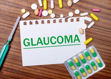 Tahta bir masa, şırınga, haplar ve üzerinde GLAUCOMA yazan bir kağıt. Tıbbi konsept