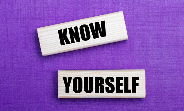 На сиреневом ярком фоне светлые деревянные блоки с текстом ЗНАЙТЕ СЕБЯ