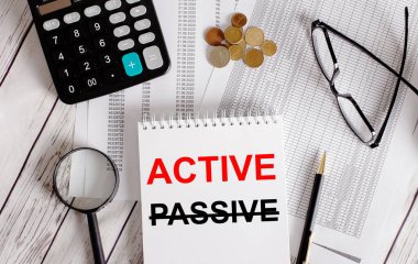 ACTIVE kelimesi hesap makinesinin yanında beyaz bir not defterine yazıldı. Para, gözlük, büyüteç ve kalem. İş konsepti