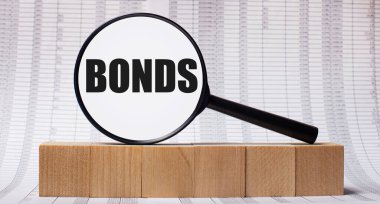 Tahta küplerle ilgili raporların arka planında BONDS yazılı bir büyüteç var. İş konsepti