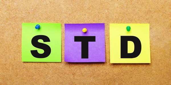 On a beige background, multi-colored stickers for notes with the word STD