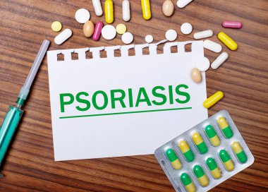 Tahta bir masa, şırınga, haplar ve üzerinde PSORIASIS yazan bir kağıt. Tıbbi konsept