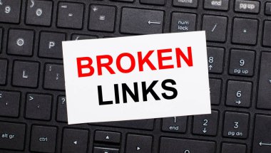 Siyah bir bilgisayar klavyesinde üzerinde Broken Link yazan beyaz bir kart var. Yukarıdan görüntüle