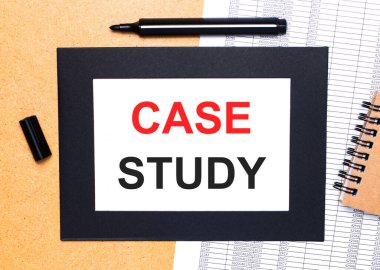 Ahşap bir masanın üzerinde, açık siyah bir kalem, kahverengi bir not defteri ve siyah çerçeveli CASE STUDY yazılı bir kağıt var. Yukarıdan görüntüle.