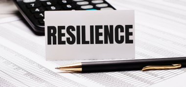 Masaüstü raporlar, bir hesap makinesi, bir kalem ve metin RESILIENCE içeren bir beyaz kart içerir. İş konsepti
