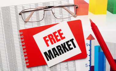 Altın çerçeveli gözlük, kırmızı kalem, renk tabloları ve masasının üstünde FREE MARKET yazılı beyaz kart olan kırmızı bir defter. İş konsepti. Yukarıdan görüntüle