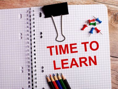 Time to Learn kelimeleri çok renkli kalemler ve ahşap arka plandaki düğmeler yakınındaki bir deftere yazılmıştır..